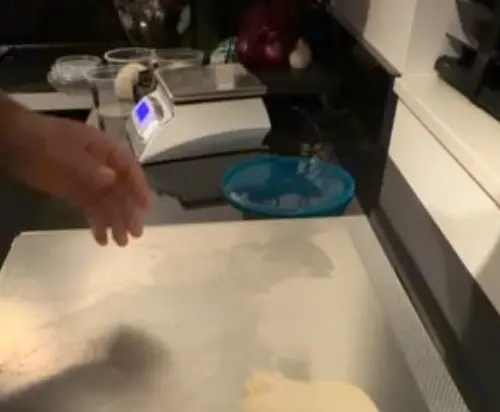 Handen die pizzadeeg vormen op een pizzastaal