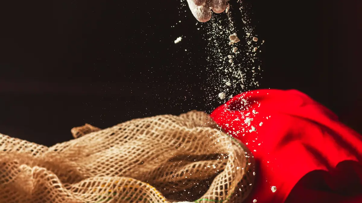 Hand die bloem strooit over pizzadeeg